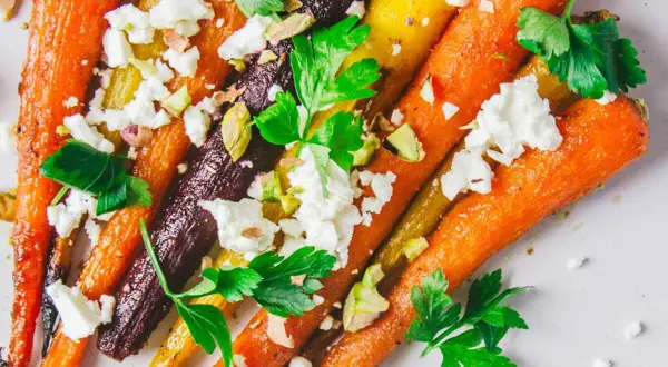 Carottes multicolores rôties, parsemées de feta émiettée, de pistaches concassées et de persil frais. Un délice pour la cuisson carottes.