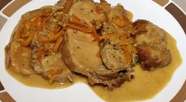 Tranches de roti de porc à l'orange, nappées d'une sauce onctueuse et garnies de zestes d'orange. Un plat savoureux et parfumé.