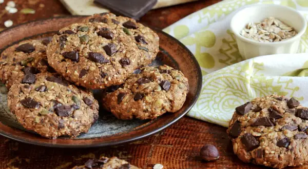 Gourmands cookies flocons d'avoine, parsemés de pépites de chocolat noir et de graines, sur une assiette rustique.