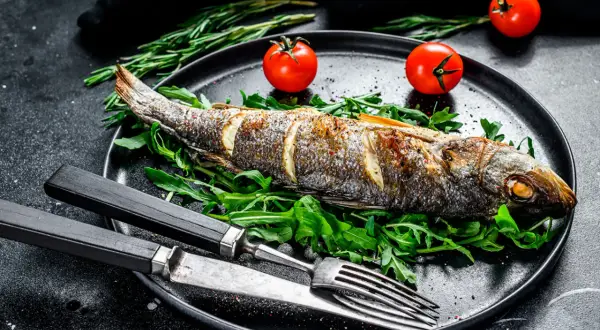 Bar entier rôti sur un lit de roquette, garni de tomates cerises. Le temps de cuisson bar au four est parfait pour ce plat savoureux.