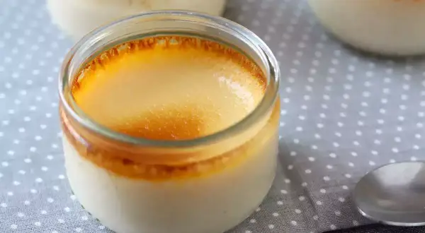 Crème aux œufs on a polka dot cloth, with a spoon nearby. The dessert has a golden, caramelized top.