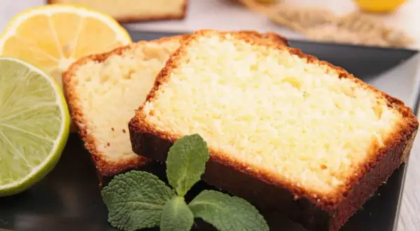 Tranches de gâteau moelleux au citron grand-mère, garnies de menthe fraîche, avec des citrons et une lime en arrière-plan.
