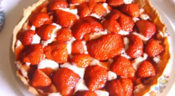 Une délicieuse tarte aux fraises, garnie de fruits rouges frais et d'une crème onctueuse, prête à être dégustée.