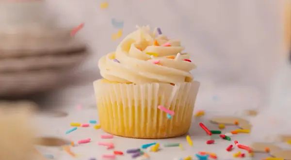 Un cupcake vanille avec glaçage crémeux et vermicelles colorés tombant. Une recette facile pour un goûter gourmand.