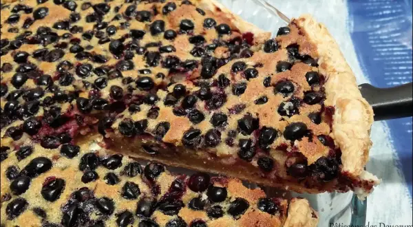 Une part généreuse de tarte aux cassis, garnie de fruits noirs juteux et d'une pâte dorée. Un délice gourmand.