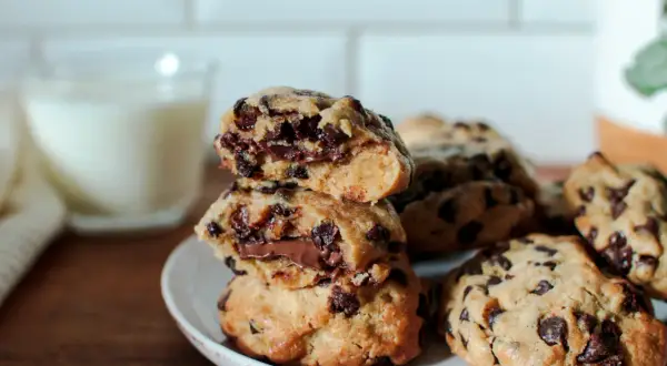 Délicieux cookies aux pépites de chocolat, parfaits pour une recette de cookies moelleux et gonflés. Un verre de lait est en arrière-plan.