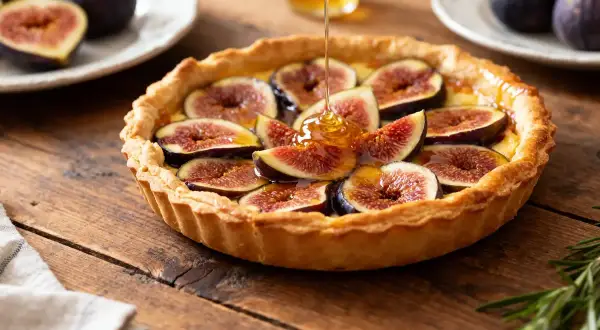La tarte aux figues de ma grand-mère, garnie de figues fraîches et nappée de miel doré, repose sur une table en bois rustique.