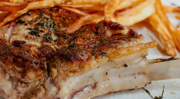 Une côte de veau au four, dorée et savoureuse, accompagnée de frites croustillantes. Un plat réconfortant pour un repas gourmand.