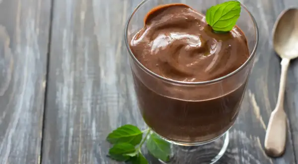 Crème au chocolat onctueuse, décorée d'une feuille de menthe, comme celle de Laurent Mariotte. Une cuillère argentée est à côté.