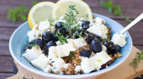 Salade de lentilles, feta, olives noires et citron, garnie de thym frais. Un délice méditerranéen.