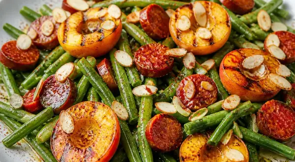 Salade de haricots verts originale avec pêches grillées, chorizo et amandes effilées. Un plat coloré et savoureux.