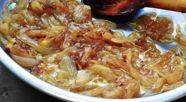 Oignons caramélisés dorés et fondants dans une poêle, prêts à sublimer un plat.