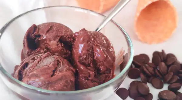 Un bol de semifreddo chocolat, avec des pépites de chocolat et des cornets à glace en arrière-plan.