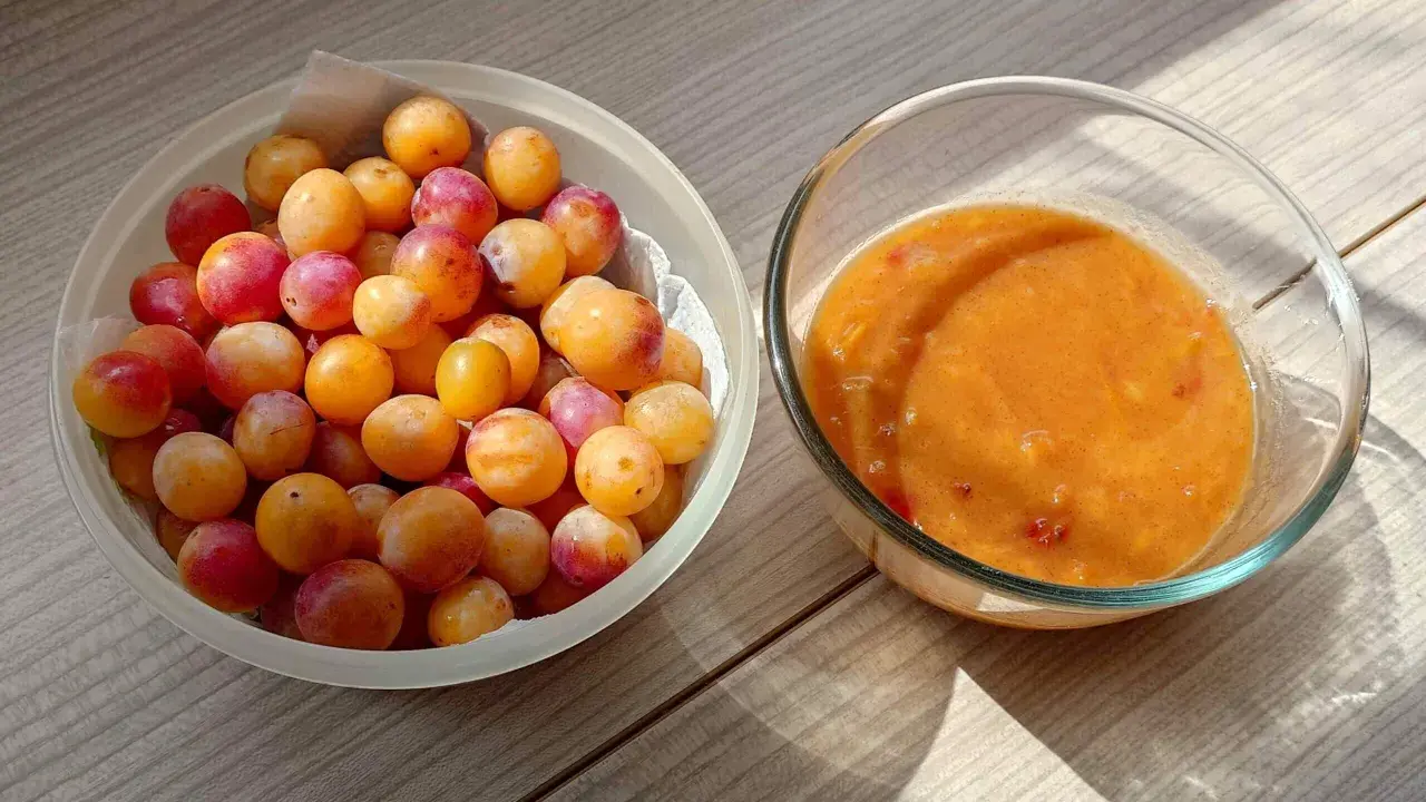 Un bol de mirabelles fraîches à côté d'un bol de compote de mirabelles maison, prêt à être dégusté.