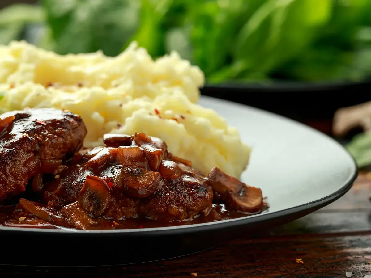 Délicieuses joue de boeuf en sauce avec des champignons, servies avec une purée de pommes de terre onctueuse.