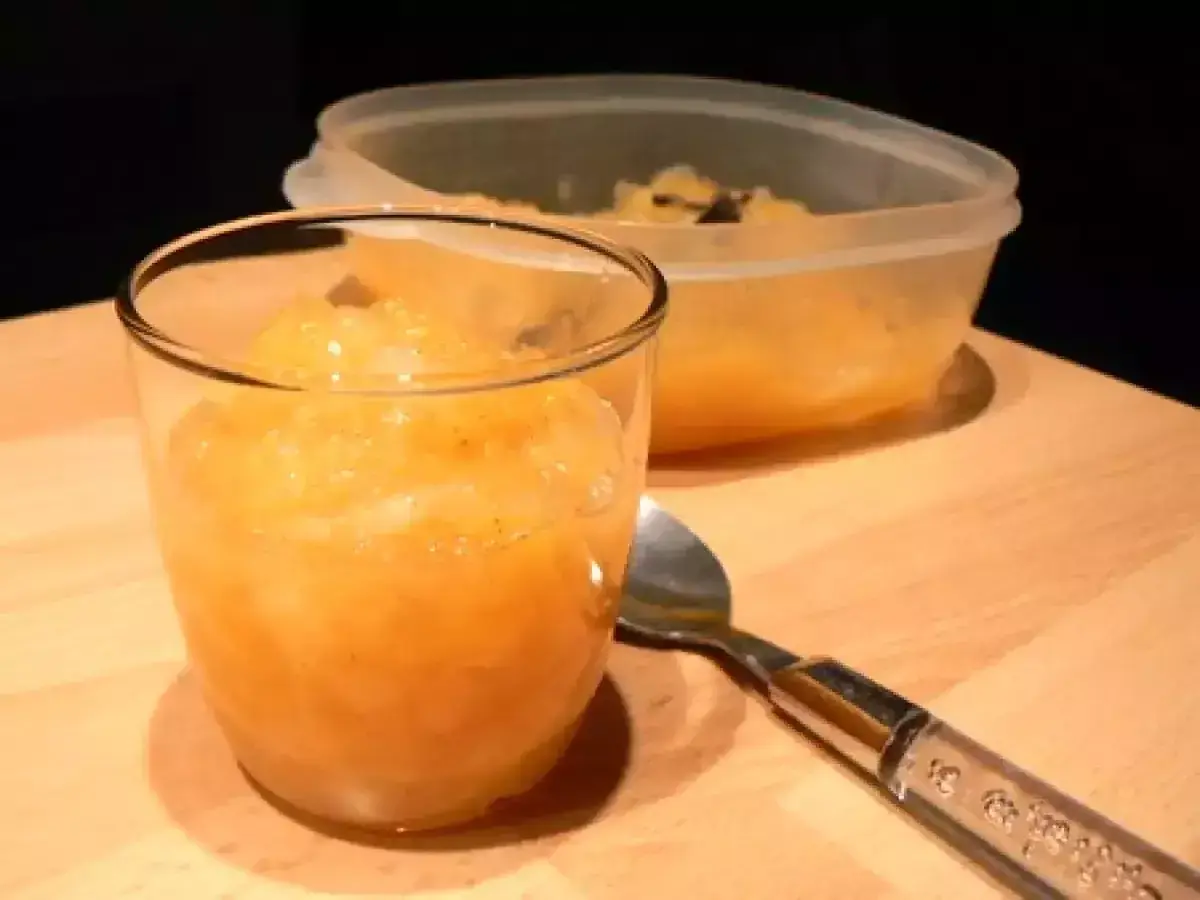 Compote pomme poire vanille dans un verre, avec une cuillère et un récipient en arrière-plan.
