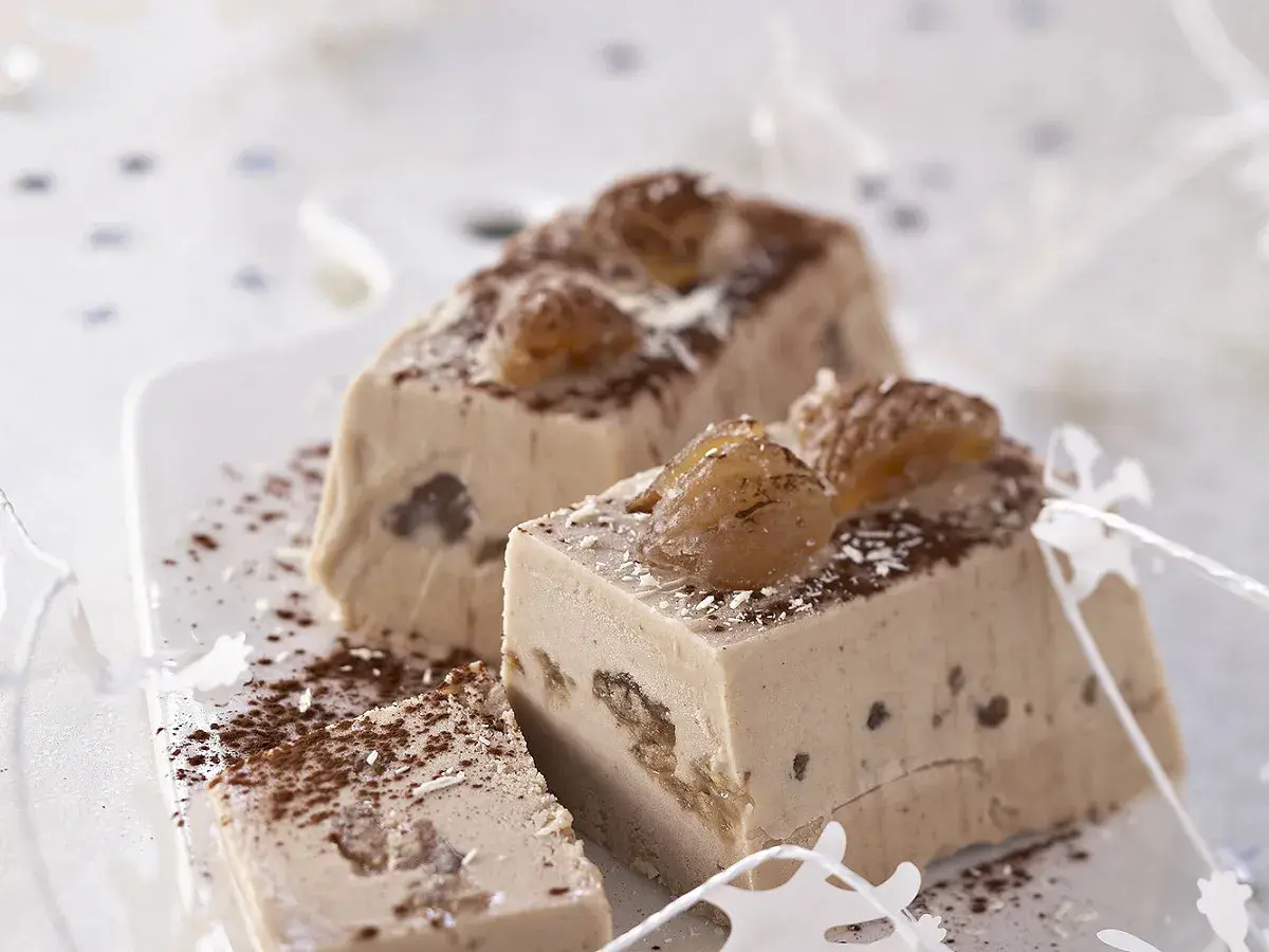 Tranches d'une délicieuse recette buche aux marrons, garnies de marrons glacés et saupoudrées de cacao.