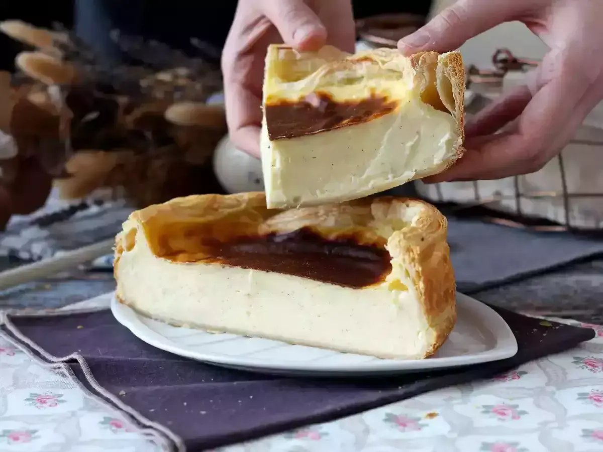Un flan pâtissier crémeux, doré et généreux, est coupé en deux. Ses bords croustillants et sa garniture onctueuse invitent à la dégustation.