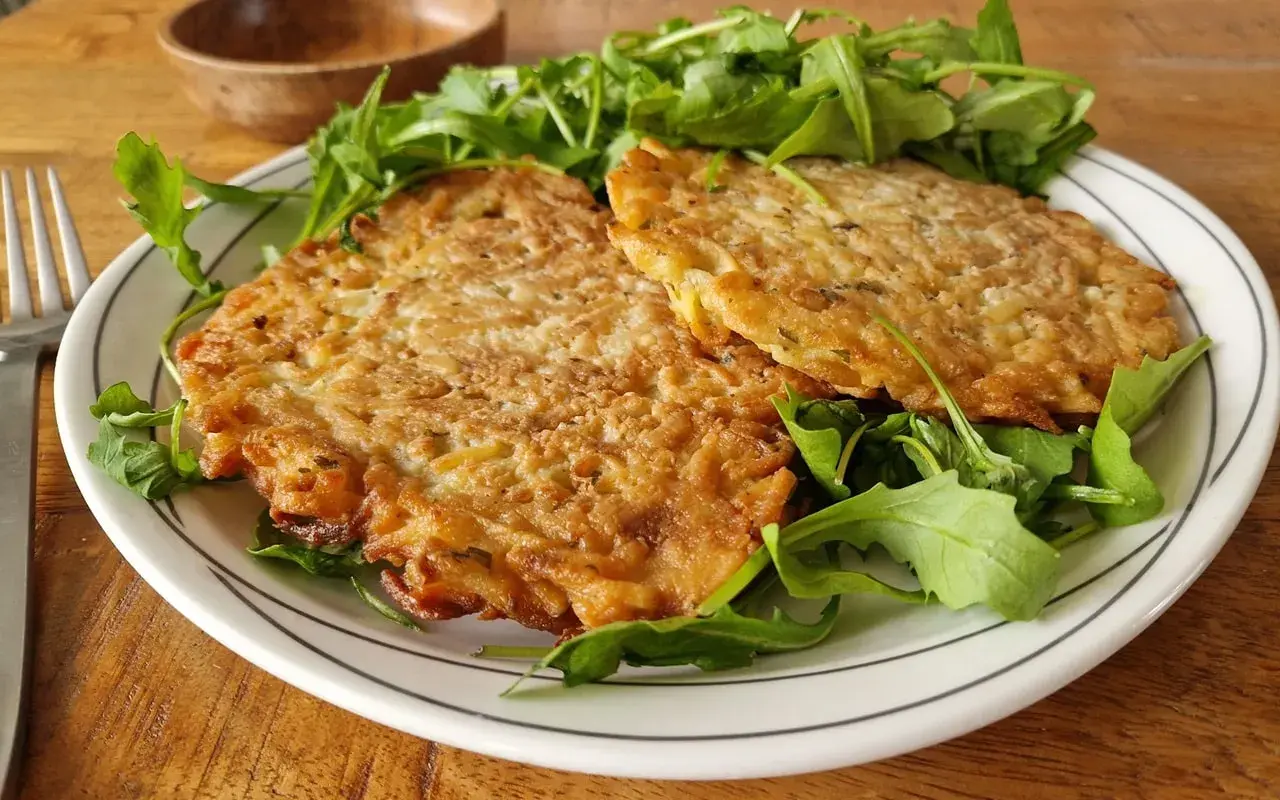 Deux galettes dorées sur un lit de roquette. Une belle assiette pour apprendre comment apprendre cuisiner.
