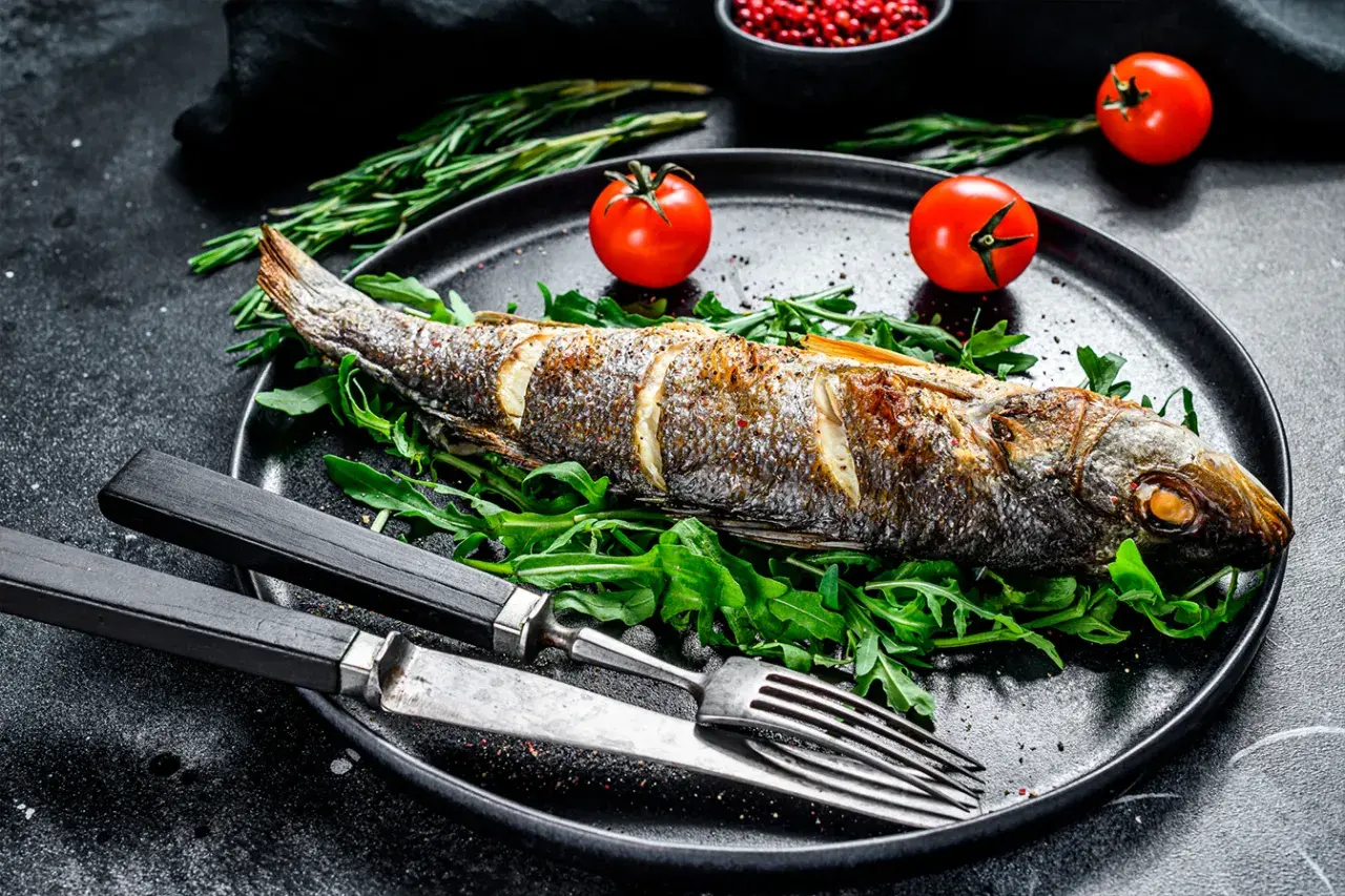Bar entier rôti sur un lit de roquette, garni de tomates cerises. Le temps de cuisson bar au four est parfait pour ce plat savoureux.