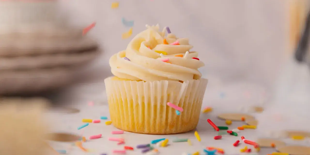 Un cupcake vanille avec glaçage crémeux et vermicelles colorés tombant. Une recette facile pour un goûter gourmand.