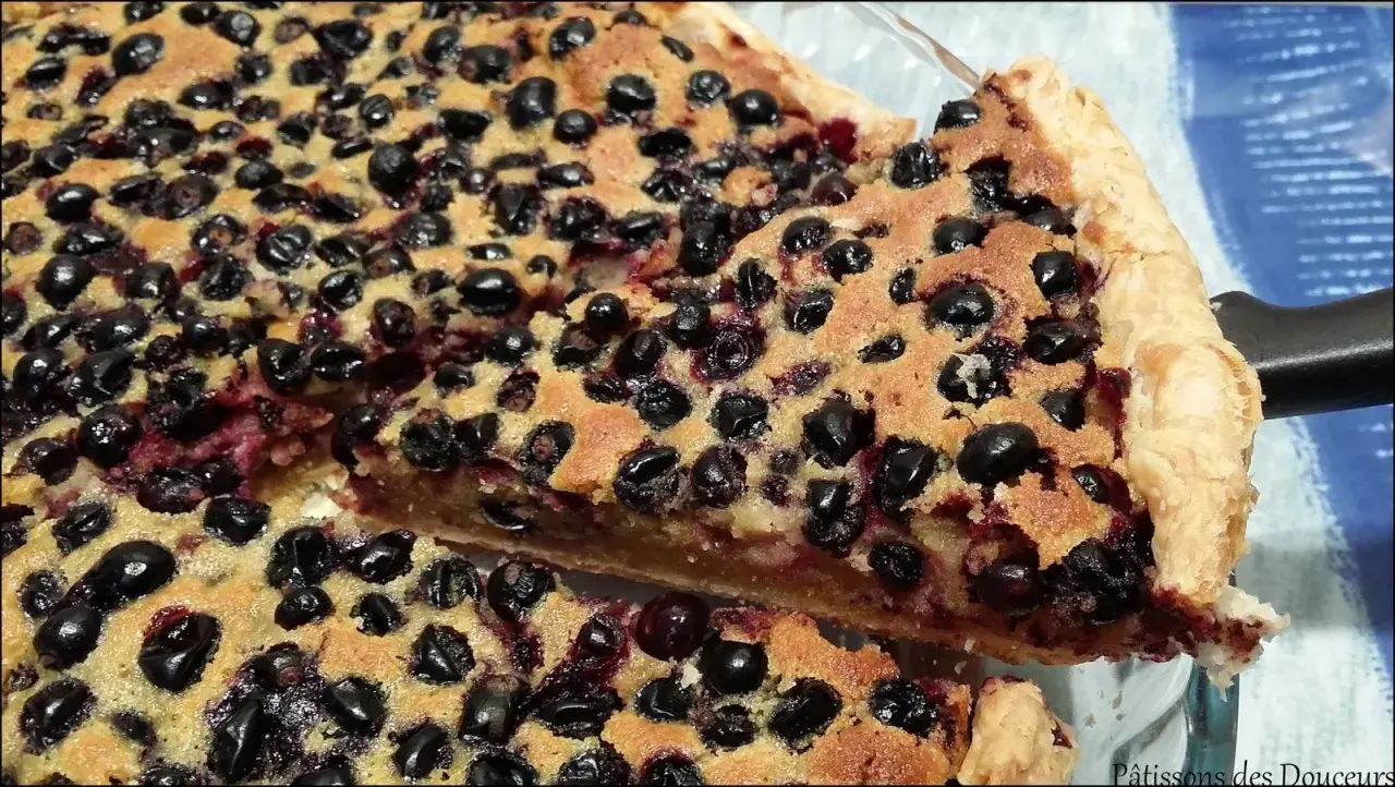 Une part généreuse de tarte aux cassis, garnie de fruits noirs juteux et d'une pâte dorée. Un délice gourmand.