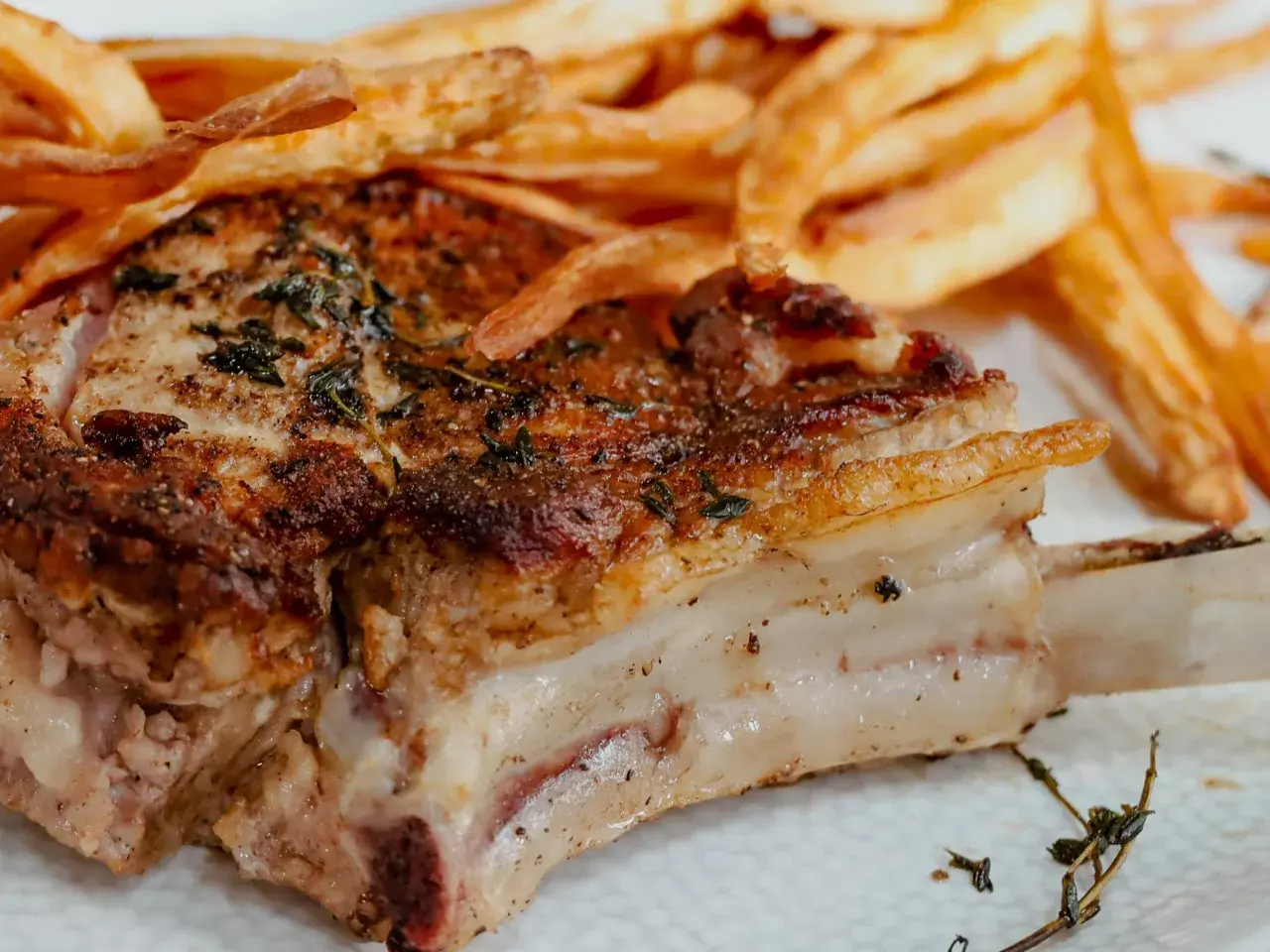 Une côte de veau au four, dorée et savoureuse, accompagnée de frites croustillantes. Un plat réconfortant pour un repas gourmand.