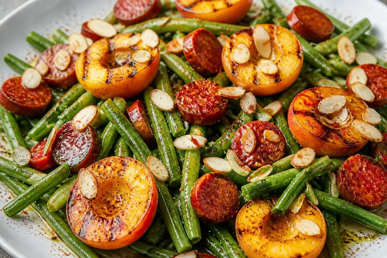 Salade de haricots verts originale avec pêches grillées, chorizo et amandes effilées. Un plat coloré et savoureux.
