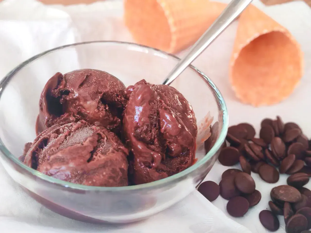 Un bol de semifreddo chocolat, avec des pépites de chocolat et des cornets à glace en arrière-plan.