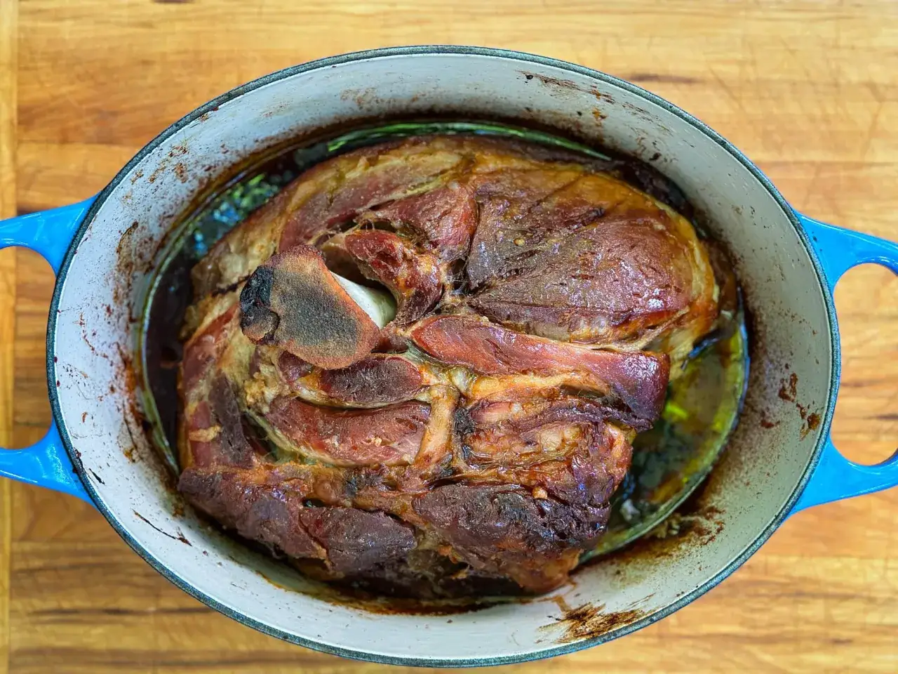 Un morceau de porc rôti dans une cocotte bleue, prêt pour une recette d'effiloché de porc.