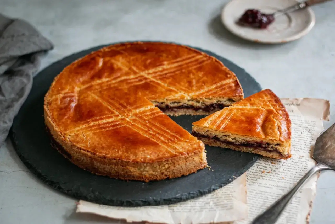 Un délicieux cheesecake basque doré, avec une garniture de confiture sombre visible, coupé en part.