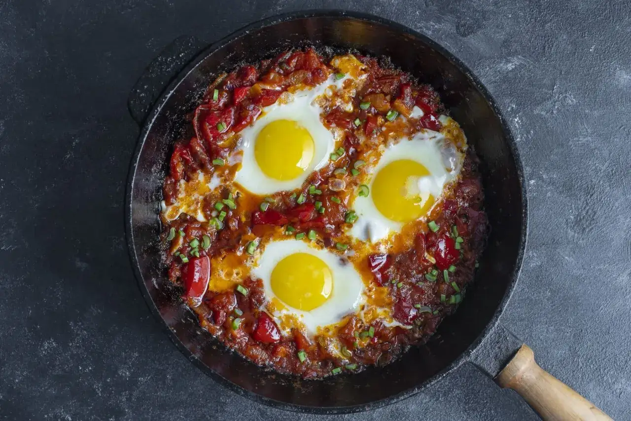 Œufs pochés dans une sauce tomate épicée, une délicieuse recette de chakchouka, garnie de ciboule fraîche.