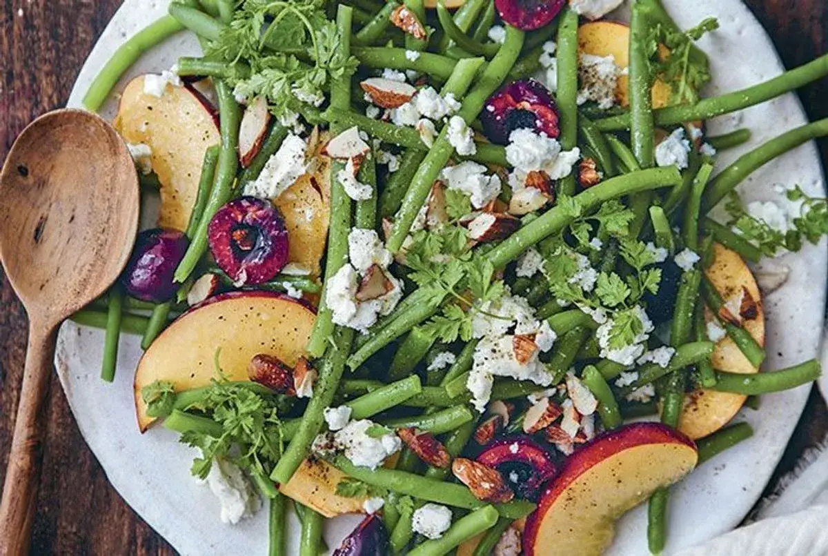 Une salade de haricots verts originale avec des pêches, des cerises, du fromage frais et des amandes effilées. Une explosion de saveurs et de couleurs.