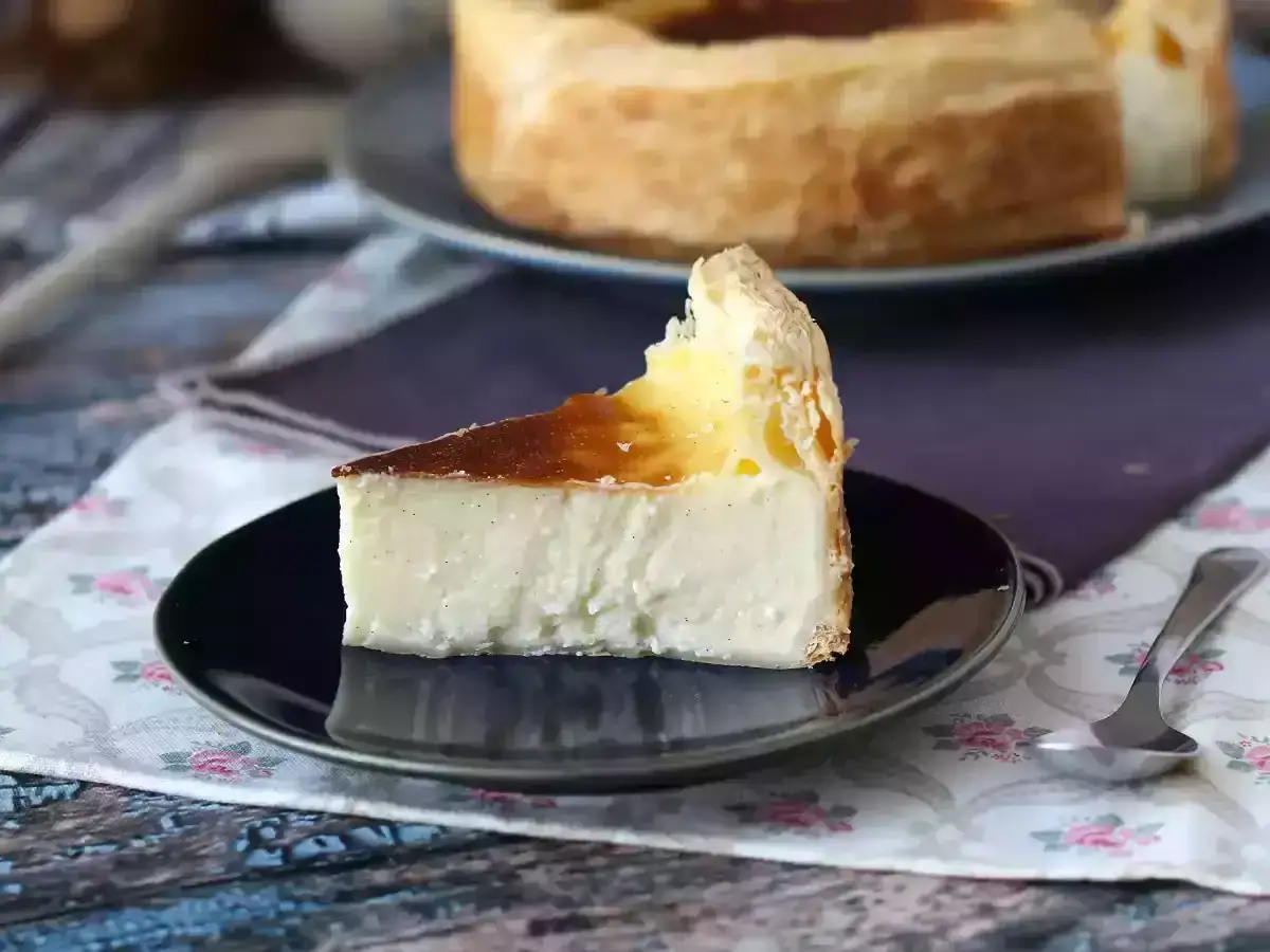 Une part de flan pâtissier crémeux, parsemé de vanille, sur une assiette noire. Un délice à savourer.
