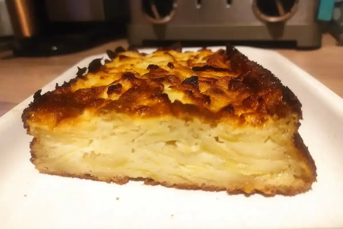 Tranche de gâteau sans sucre aux pommes, dorée et appétissante, servie sur une assiette blanche.