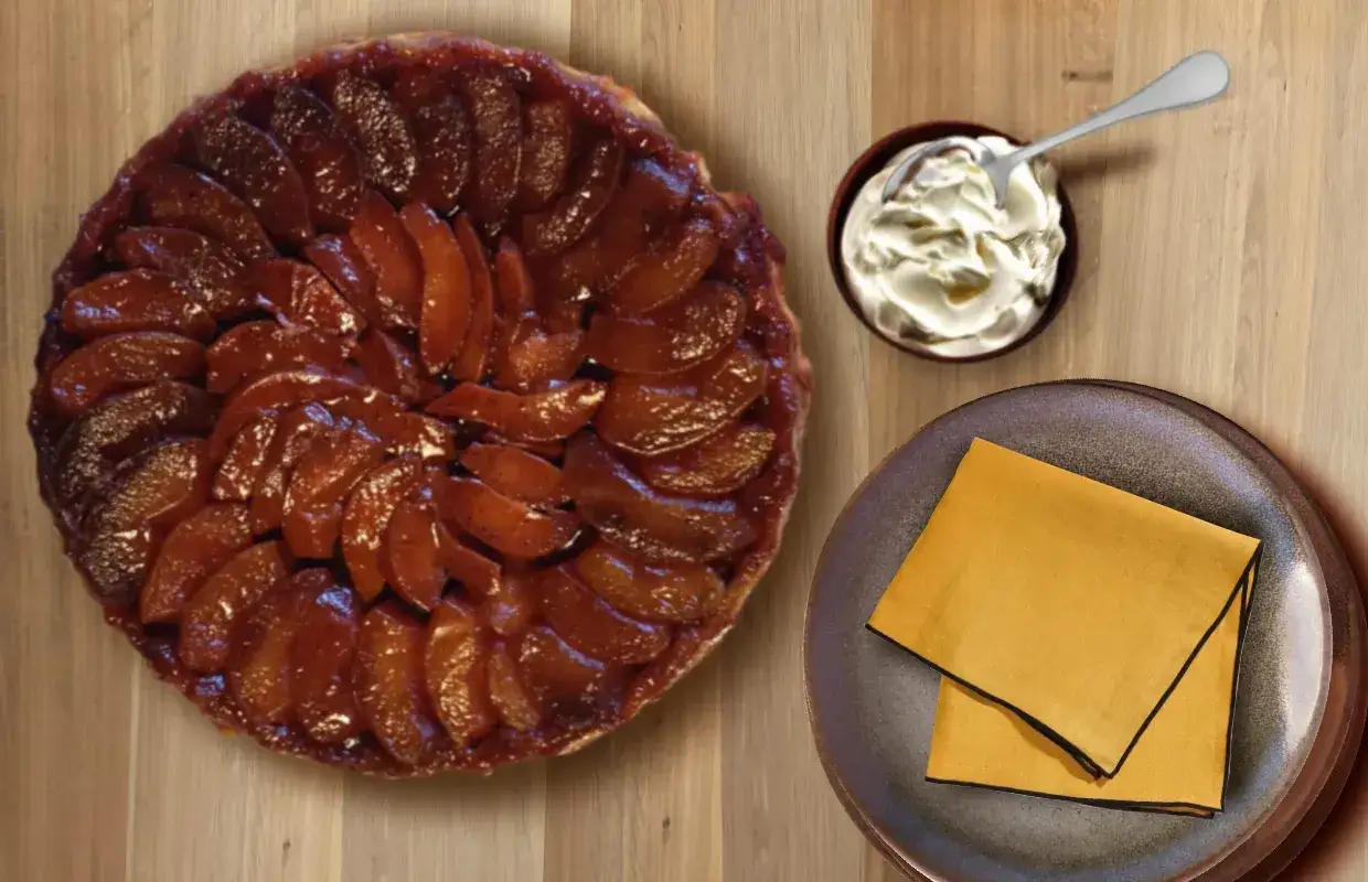 Une délicieuse tarte tatin aux pommes caramélisées, servie avec une cuillère de crème fouettée.