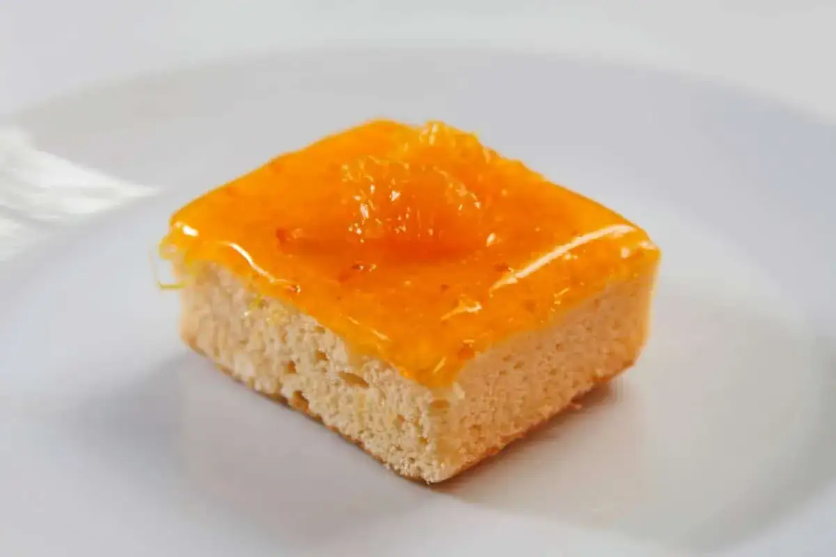 Un carr&eacute; de g&acirc;teau au gingembre, napp&eacute; d'un gla&ccedil;age orange vif et garni d'une tranche d'agrume confit.