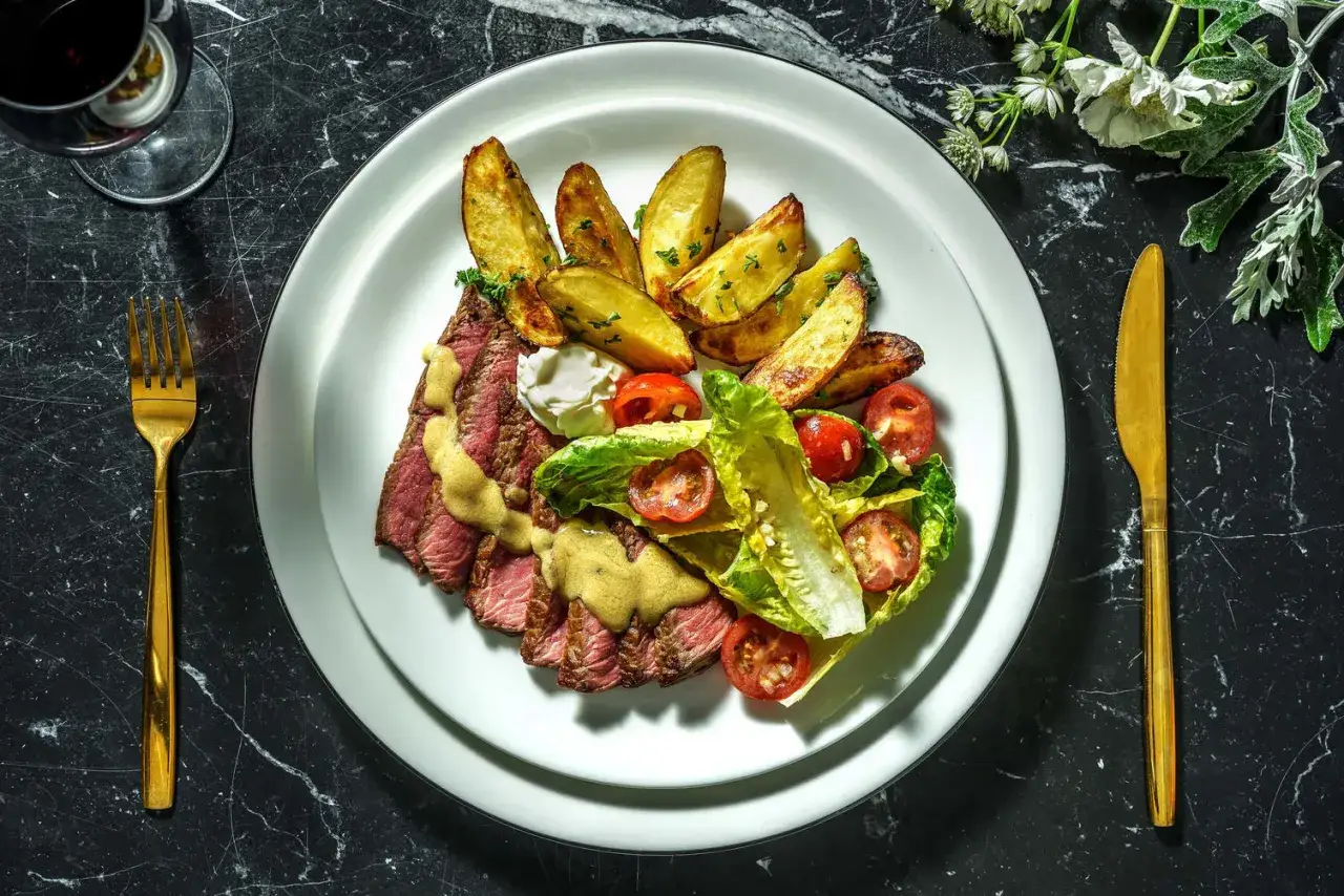 Une savoureuse entrecôte au four, tranchée et nappée d'une sauce onctueuse, accompagnée de pommes de terre rôties et d'une salade fraîche.