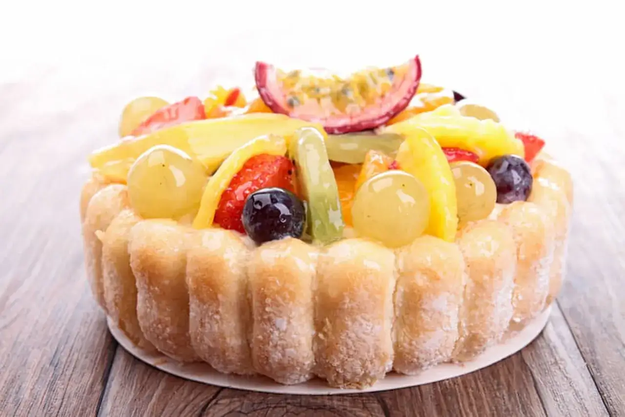 Une d&eacute;licieuse charlotte aux fruits, garnie de fraises, mangues, kiwis, raisins et fruits de la passion.