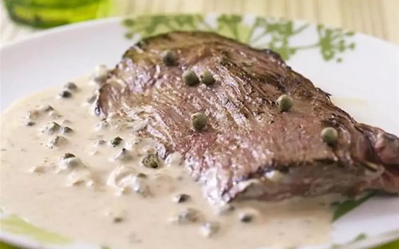 Une bavette de bœuf généreuse, nappée d'une onctueuse sauce poivre crémeuse, parsemée de grains de poivre vert. Un délice !