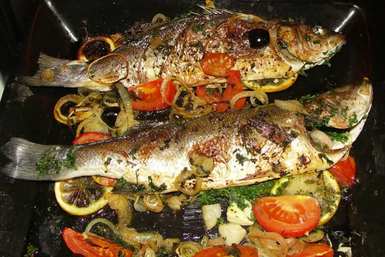 Deux bars entiers, dorés et savoureux, prêts à être dégustés. Le temps de cuisson au four a été parfait pour ce plat méditerranéen avec citrons, tomates et olives.