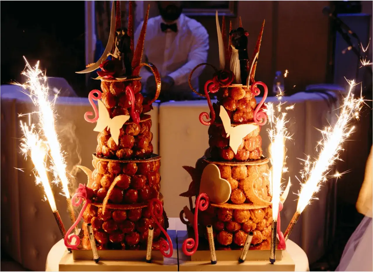 Deux magnifiques g&acirc;teaux des mari&eacute;s, orn&eacute;s de figurines, papillons et c&oelig;urs, illumin&eacute;s par des feux de Bengale &eacute;tincelants.