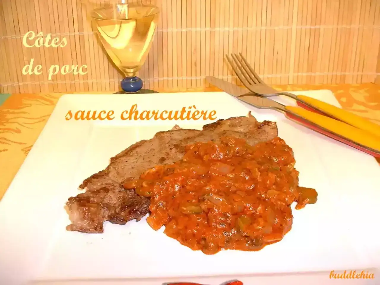 Une c&ocirc;te de porc savoureuse napp&eacute;e d'une sauce charcuti&egrave;re maison, accompagn&eacute;e d'un verre de vin blanc.