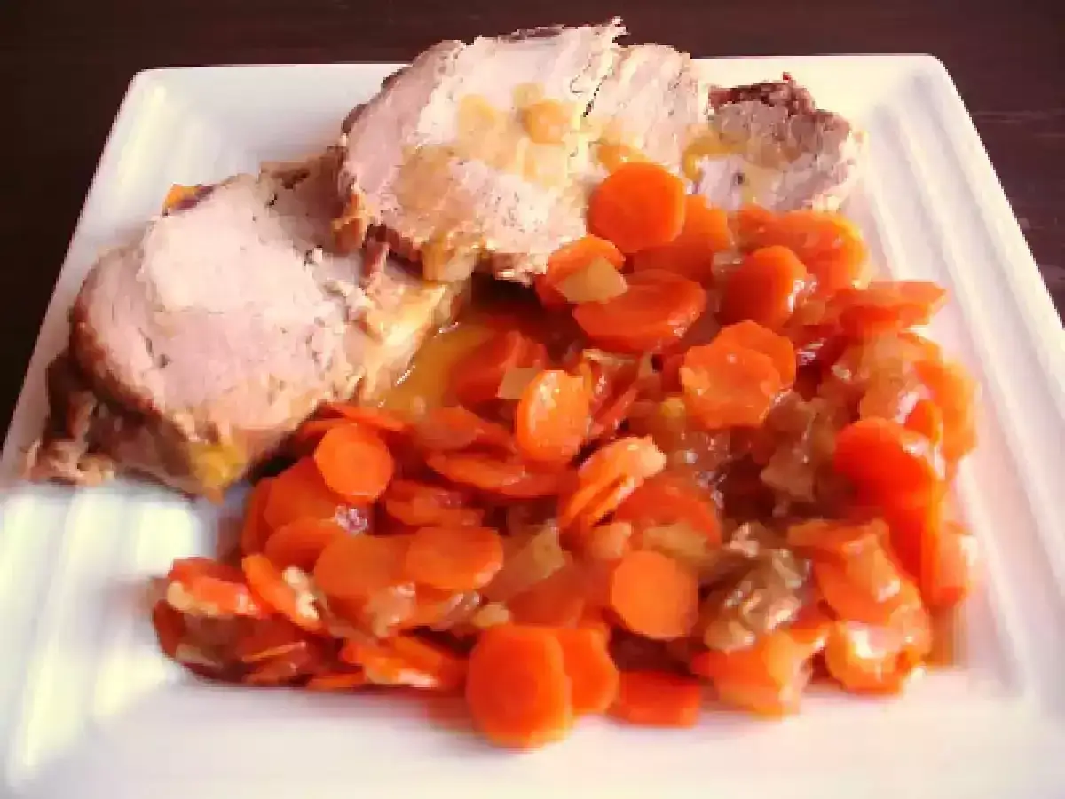 Tranches de roti de porc &agrave; l'orange, napp&eacute;es de jus, servies avec des carottes coup&eacute;es en rondelles et mijot&eacute;es.