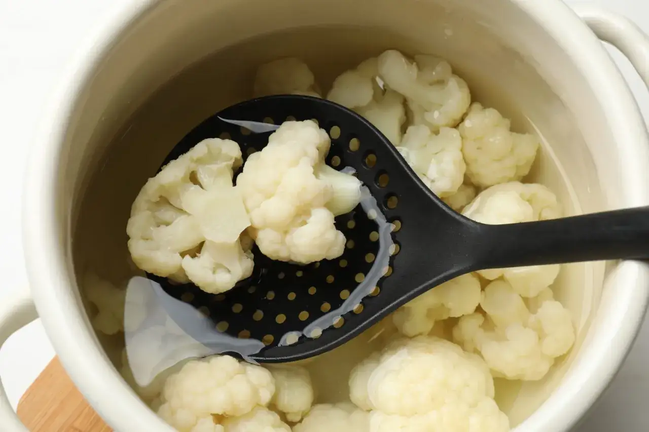 Cuisson du chou-fleur dans de l'eau. Une louche ajour&eacute;e retire des fleurettes de ce l&eacute;gume blanc, pr&ecirc;t &agrave; &ecirc;tre cuit &agrave; l'eau froide ou chaude.