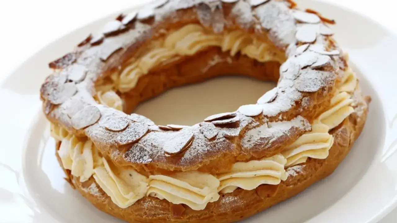 Un Paris Brest, délicieux dessert en forme de couronne, garni de crème onctueuse et d'amandes effilées. Une recette à essayer !