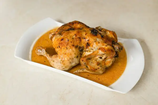 Un délicieux poulet entier, d'environ 1,5 kg, est prêt pour la cuisson au four, sa peau dorée promet un plat savoureux.