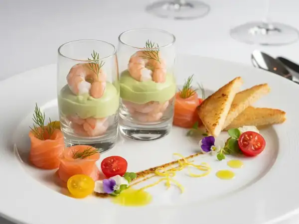 Une élégante entrée froide : crevettes et avocat en verrine, saumon roulé, toasts grillés et garnitures fraîches.