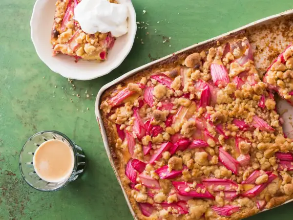Un délicieux crumble pomme Laurent Mariotte, garni de fruits rouges et d'une touche de crème, prêt à être dégusté avec un café.