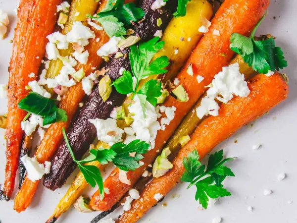 Carottes multicolores rôties, parsemées de feta émiettée, de pistaches concassées et de persil frais. Un délice pour la cuisson carottes.
